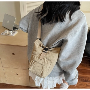 Sac à bandoulière en nylon froissé kaki porté par un mannequin dans un intérieur
