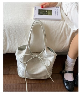 Close-up of white lace texture and ribbon bow detail on the bucket handbag