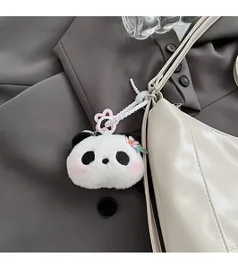 Détail d'un charmant panda en peluche avec fleur rose attaché à un sac à main beige