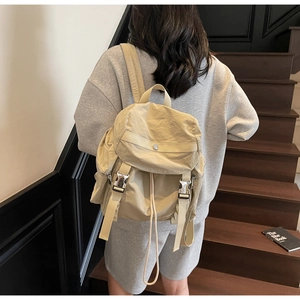 Vista laterale di donna con zaino in nylon crema sulle scale con chiusura a coulisse