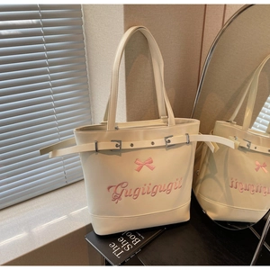 Gros plan du sac cabas beige avec broderie nœud rose et détails de sangles à boucles