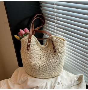 Gros plan sur un sac de plage tissé crème avec des bandoulières en similicuir marron