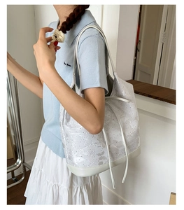 Detailed shot of white shoulder bag featuring floral embroidery and leather stitching