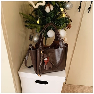 Detail of dark brown leather handbag with polo engraving and cute bear charm pendant