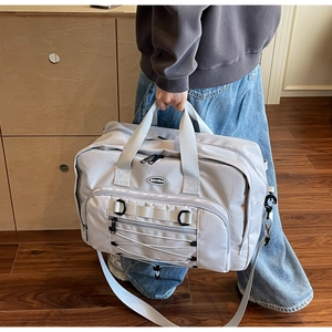 Close-up of light grey nylon travel bag with crossbody strap and elastic cord detail