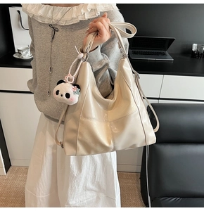 Détail d'un sac cabas beige brillant avec un charmant pendentif panda et coutures quadrillées
