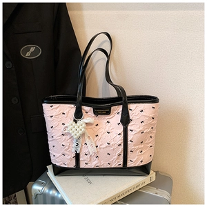 Detailed view of pink tote with bow patterns, pearl heart charm and black patent trim