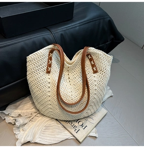 Détail de la couture en croix sur la poignée en cuir d'un sac de plage en paille