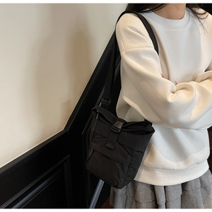Detalle del bolso de nailon negro minimalista con correa ajustable y cierre de hebilla negra