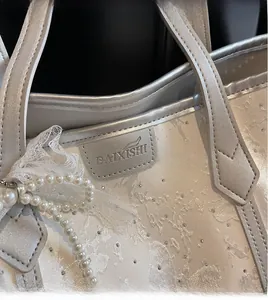 Dettaglio borsa shopper bianco perla con pizzo elegante e tracolla di perle fine