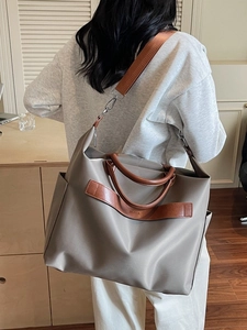 Grand sac cabas gris en nylon avec poignées en cuir et bandoulière dans un bureau