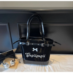 Détail du grand sac cabas en cuir verni noir avec sangles à boucle argentée et petit nœud