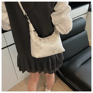 Detailed shot of white butterfly embossed shoulder bag with pearl drawstring on a model
