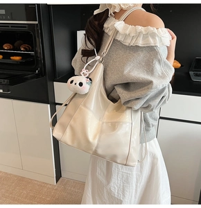 Gros plan d'un sac cabas crème matelassé avec un charmant porte-clés panda en peluche