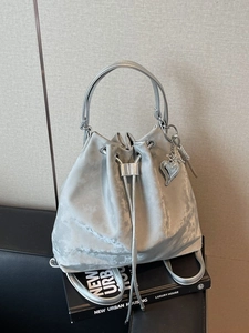Silver bucket bag with drawstring closure and metallic finish on luxury books