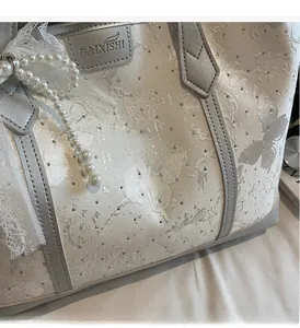 Dettaglio della borsa tote jacquard argento con strass e fiocco di perle e pizzo