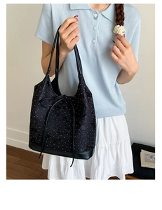 Detail of black jacquard bucket bag with white dot texture and delicate bow decoration