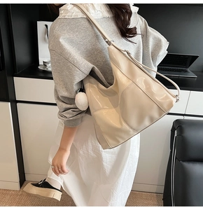 Détail du sac cabas en cuir verni blanc cassé avec pompon en peluche dans un bureau