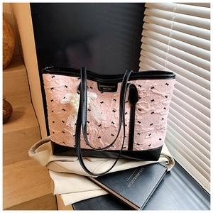 Detail of pink embossed tote bag with black bow patterns and luxury pearl charms