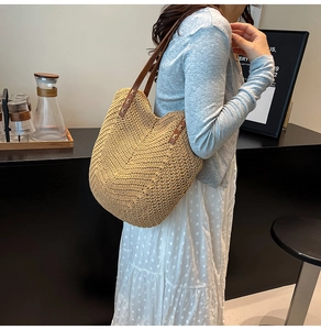 Détail du sac de plage tressé avec bretelles en cuir marron et rivets métalliques voyage