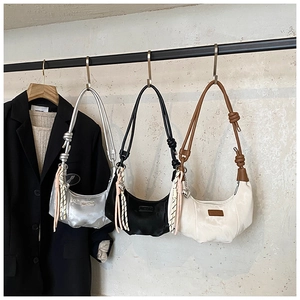 Detailed view of dumpling bags in silver, black and white with knotted rope straps