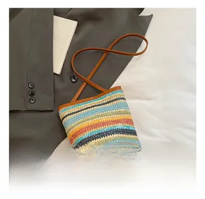Detail of colorful striped woven straw bucket bag with brown leather shoulder strap texture