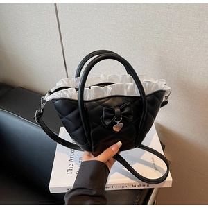 Close-up of black quilted bucket bag with bow detail and white ruffle interior trim