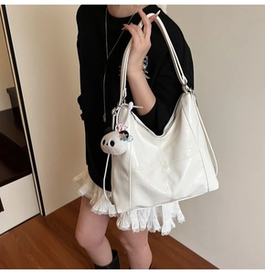 Détail du sac cabas en similicuir blanc crème avec coutures et pendentif panda
