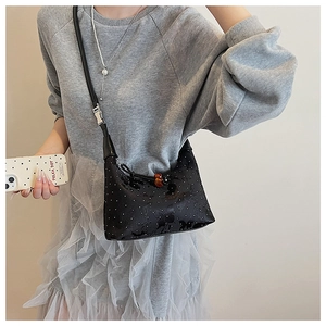 Detail of black crossbody bag featuring white polka dots and butterfly patterns with metal buckle