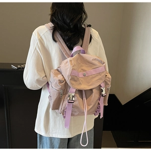 Modello indossa uno zaino in nylon beige con cinturini viola e fibbie argentate lucide