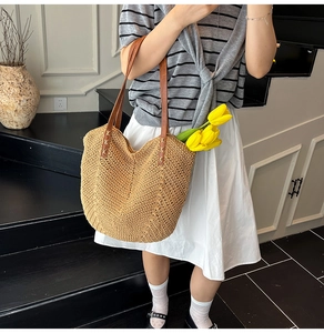 Détail d'un sac cabas en paille tissée avec texture en V et anses en cuir marron