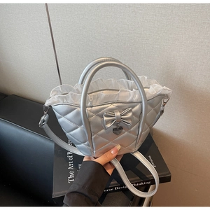 Detail view of silver quilted handbag with heart pendant and white lace ruffles liner