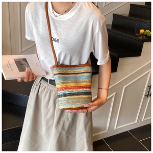 Detailed view of a colorful striped woven bucket bag with brown leather trim and strap