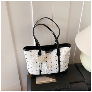 Detailed view of tote bag featuring black and white textures and pearl heart charm