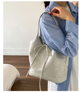 Elegant cream bucket bag with rhinestone embellishments and a delicate bow detail