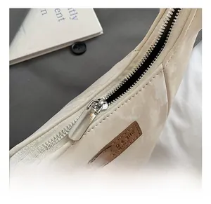 Detail of silver zipper and MIAO & SHE FASHION leather tag on beige dumpling bag