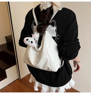 Détail du sac hobo blanc crème avec pendentif panda sur une tenue décontractée