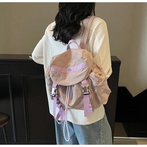 Vista posteriore di una modella con lo zaino in nylon viola chiaro in interni moderni