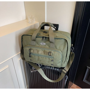 Detailed view of the large olive green canvas travel bag placed on a suitcase handle