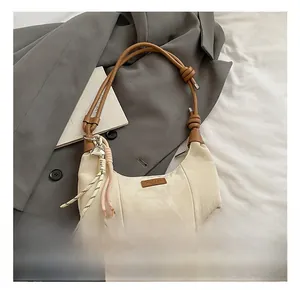 Detail view of cream crescent bag with pleated nylon fabric and woven tassel heart pendant