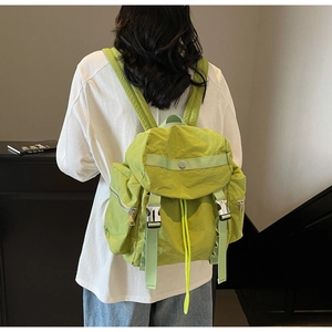 Dettaglio dello zaino in nylon verde brillante con coulisse e fibbie gialle a contrasto