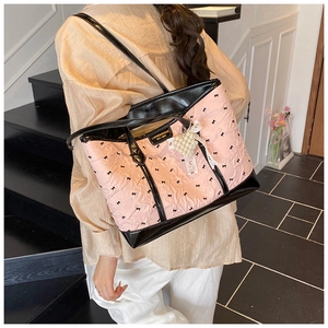 Detailed close-up of pink quilted tote bag with black bows and a pearl heart charm