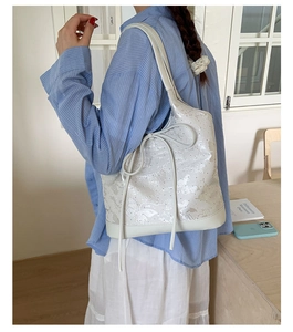 Detail view of white shoulder bag with butterfly patterns and ribbon decoration