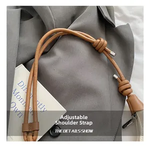 Detail of adjustable brown leather shoulder strap with elegant knot and silver metal tips