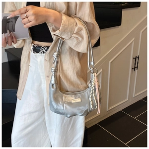 Close-up of metallic silver crescent bag with knotted strap and braided rope charm detail