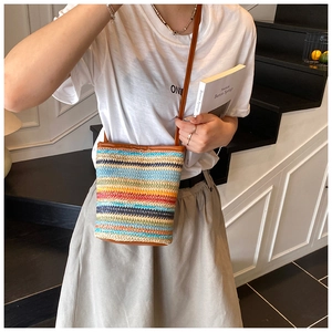 Detail of colorful striped woven bucket bag with brown leather shoulder strap for summer