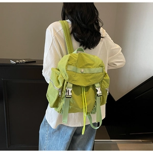 Vista posteriore di una modella con zaino in nylon verde lime con patta e fibbie doppie