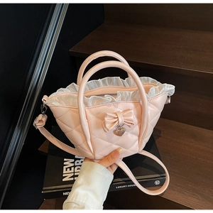 Detail of pink quilted bucket bag with white mesh ruffles and a heart pendant