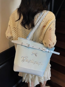 Grand sac cabas bleu clair avec nœud et broderie porté à l'épaule par un mannequin