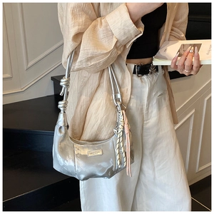 Detail of silver metallic hobo bag with pleated texture and stylish knotted shoulder strap